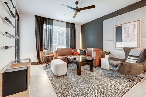 A living room with a brown and white sofa, a white ottoman, and a television.